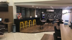 A snack bar area with a counter, yellow stools, and black chairs. - Master Express Lima e Silva (Porto Alegre)