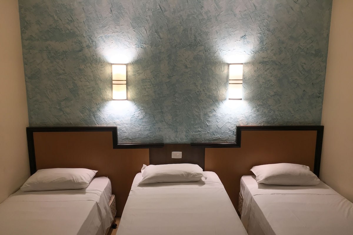 Ein Hotelzimmer mit zwei Einzelbetten, einer strukturierten Decke und zwei Wandleuchten.