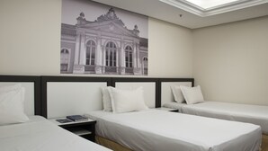 A hotel room with two single beds, a nightstand with a book, and a large poster of a classical building on the wall. - Master Grande Hotel (Porto Alegre)