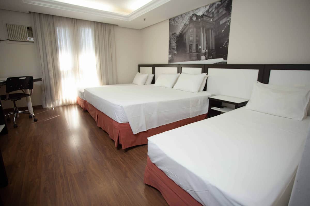 A hotel room with two beds, a desk, and a chair.
