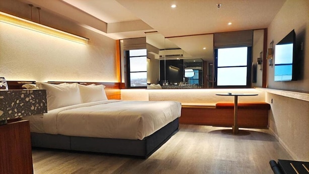 Een moderne hotelkamer met een groot bed, een klein tafeltje en een zithoek.