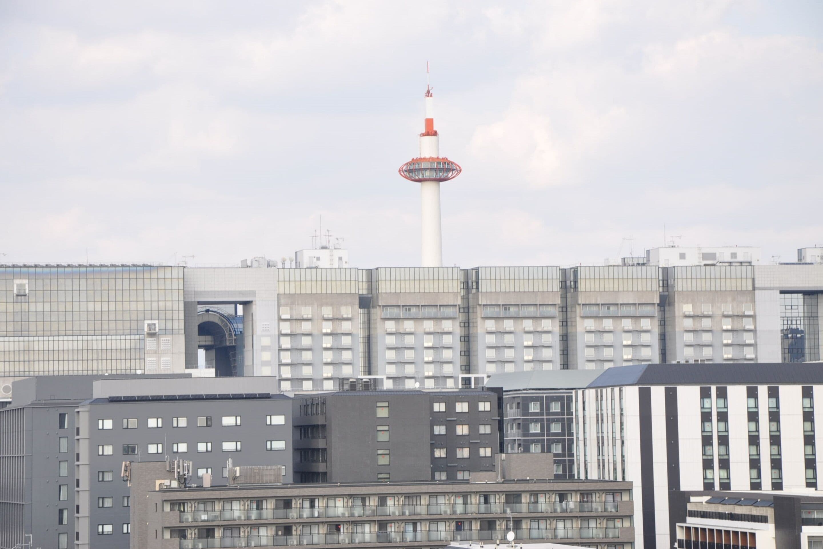 A cityscape with modern buildings and a prominent tower with a red and white top.