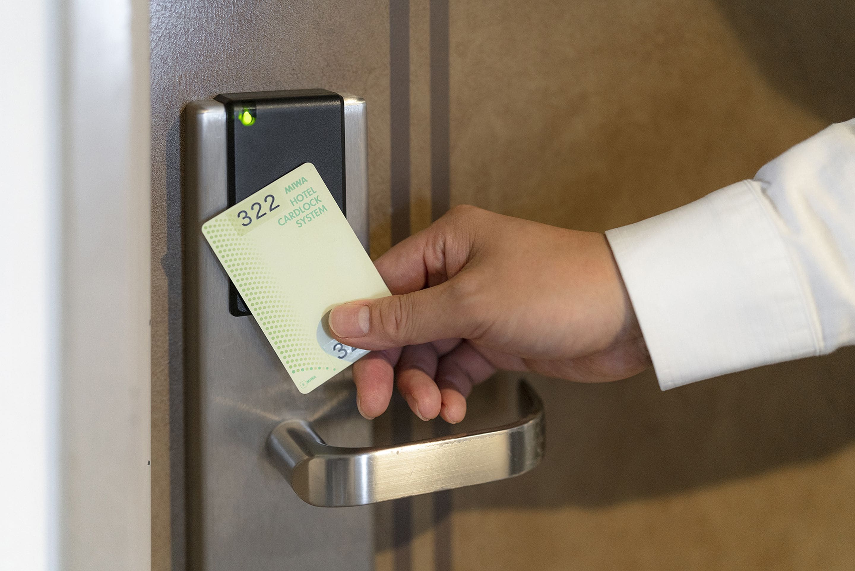 Une main insère une carte dans un lecteur de carte, probablement pour accéder à une pièce ou effectuer un paiement.