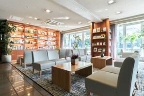 Un moderno vestíbulo de hotel con una amplia estantería, asientos cómodos y ventanas grandes.