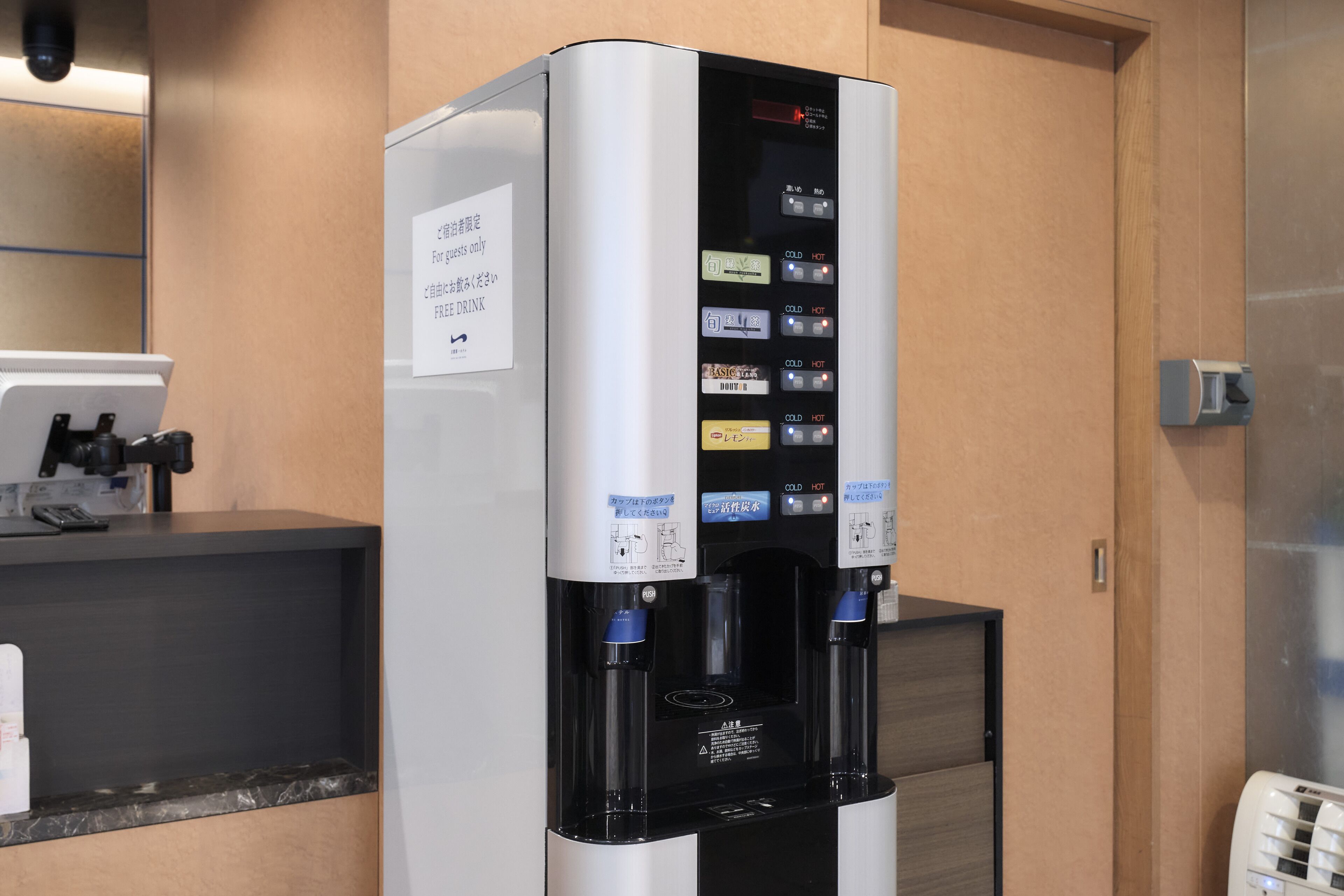 Un dispensador de bebidas automático con varias opciones, una pantalla digital y un letrero que indica que es solo para huéspedes.