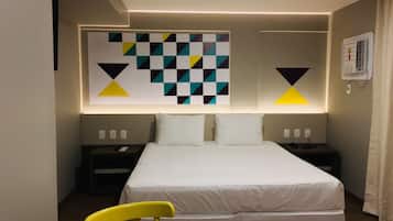 A hotel room with a bed, two bedside tables, a chair, and a geometric wall decoration.