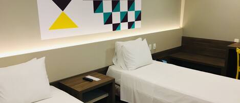 A hotel room with two single beds, a nightstand, a wall-mounted artwork, and a wooden bench.