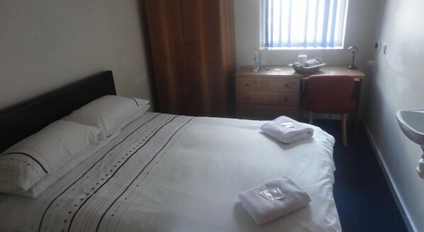 A hotel room with a bed, a desk, a chair, and a window with curtains. - Royal Chambers (Liverpool)