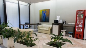 A reception area with a sofa, a desk, a vending machine, and potted plants. - Master Express Alberto Bins (Porto Alegre)