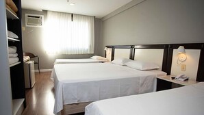 A hotel room with two beds, a wardrobe, a desk with a lamp, and an air conditioning unit. - Master Express Alberto Bins (Porto Alegre)