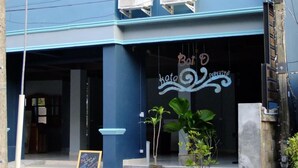 Un edificio a due piani con facciata blu, condizionatori d'aria sulla facciata esterna, una scala che conduce all'ingresso e un cartello con testo.