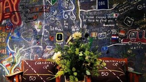 Una stanza con un muro coperto di graffiti, due sedie di legno con cuscini e una pianta in vaso su un tavolo di legno.
