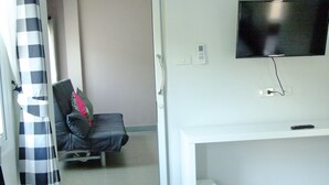 Una camera d'albergo con un letto, una scrivania, una sedia, una televisione e un bagno.