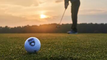 A golf ball on a green with a golfer in the background.