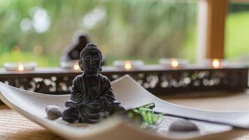 A Buddha statue on a white tray with a candle holder in the background.
