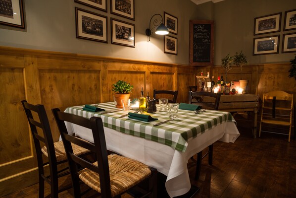 Un comedor con mantel a cuadros, sillas de madera, una planta en maceta y una vela encendida.
