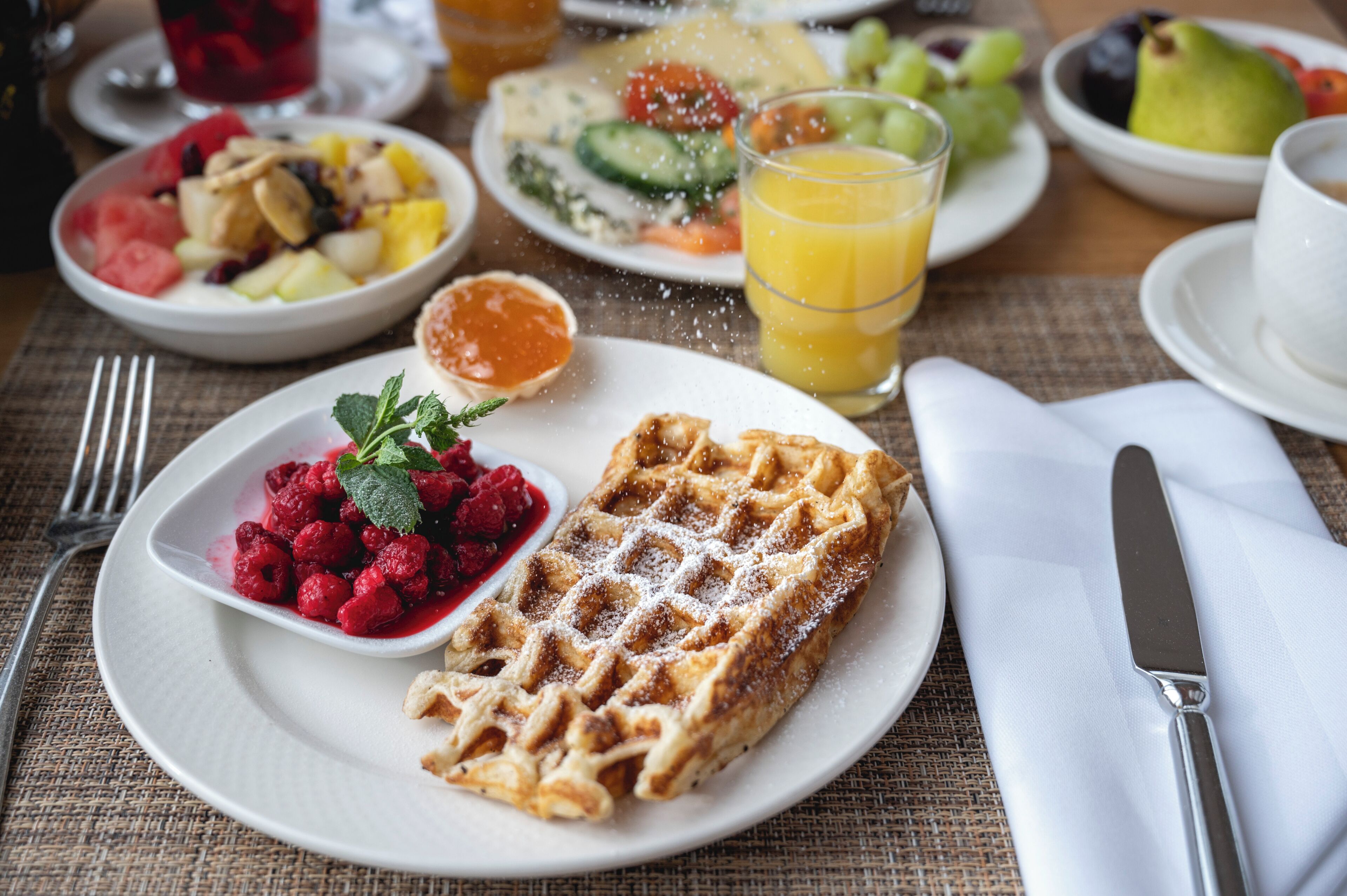 A breakfast setting with waffles, fruit, and juice.