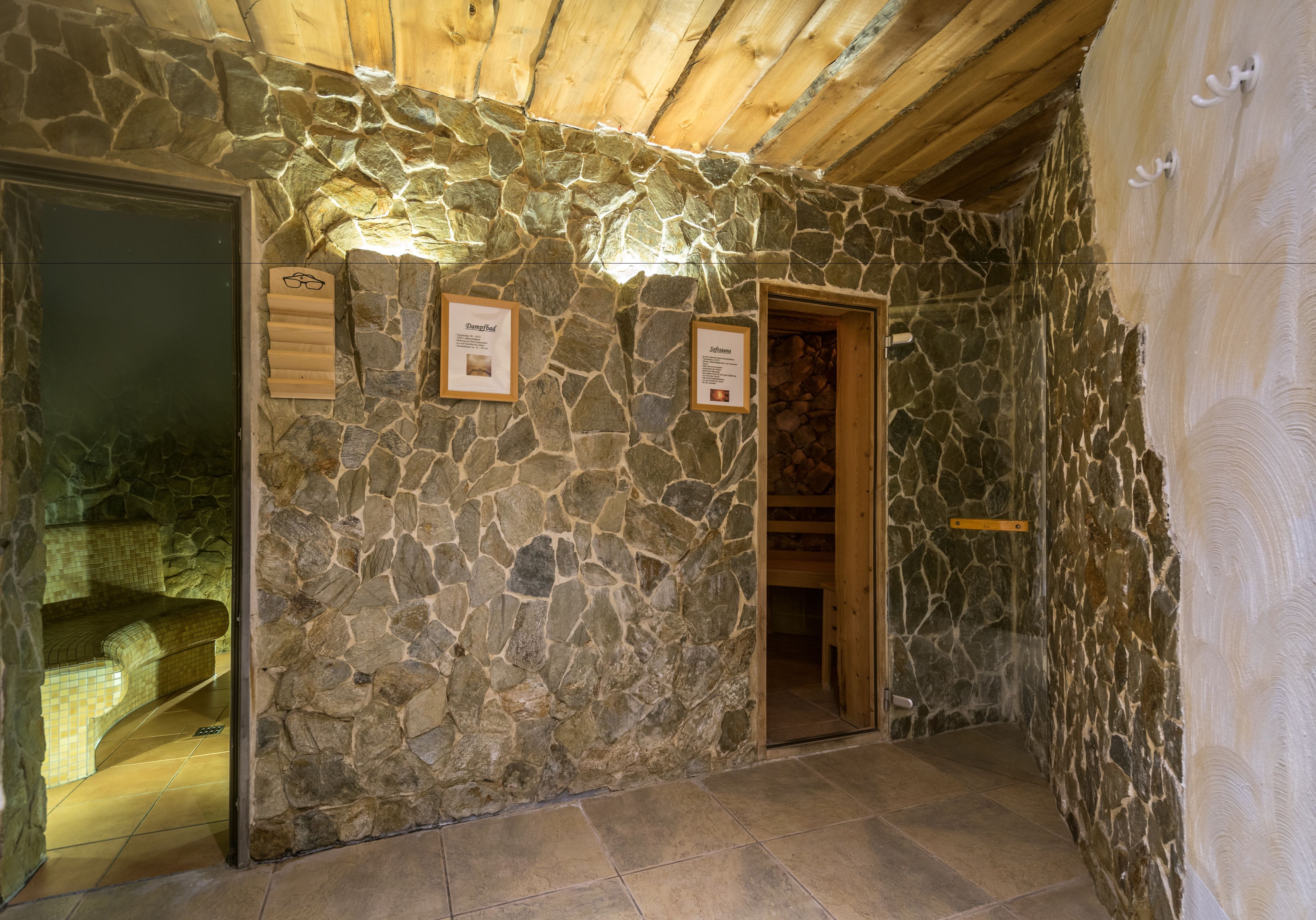 A stone-walled room with a wooden ceiling, a door, and a framed sign on the wall.