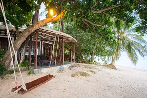 A wooden swing under a tree, a wooden structure with a roof, and a beach with palm trees. - B52 Beach Resort (Ko Pha-ngan)