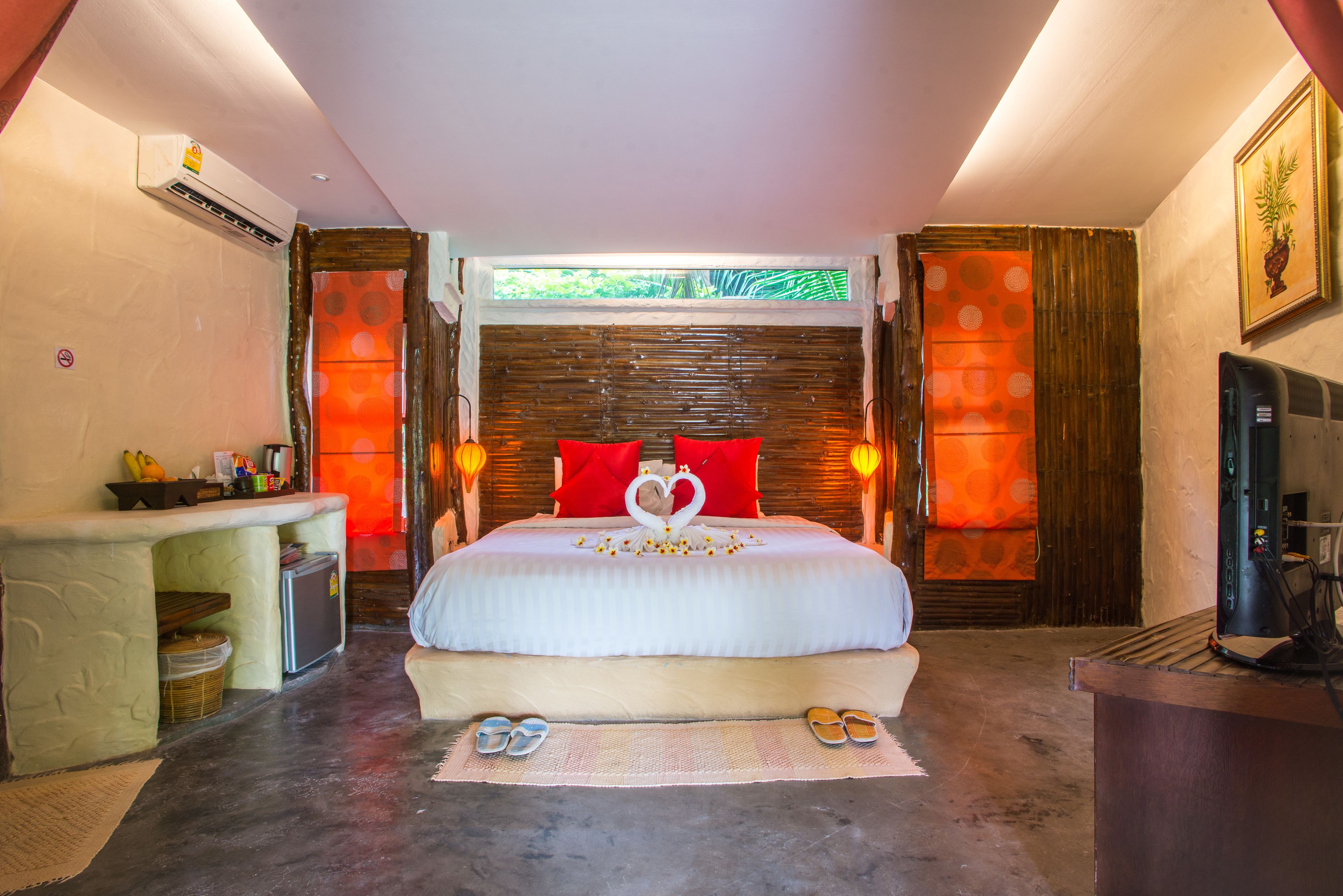 A hotel room with a bed, a desk, a television, and a window with a view of greenery.