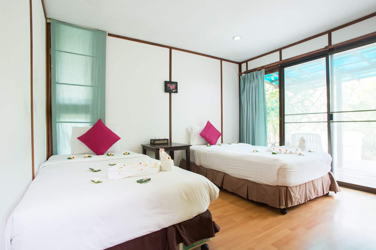 A hotel room with two beds, a small table, and a window with curtains.