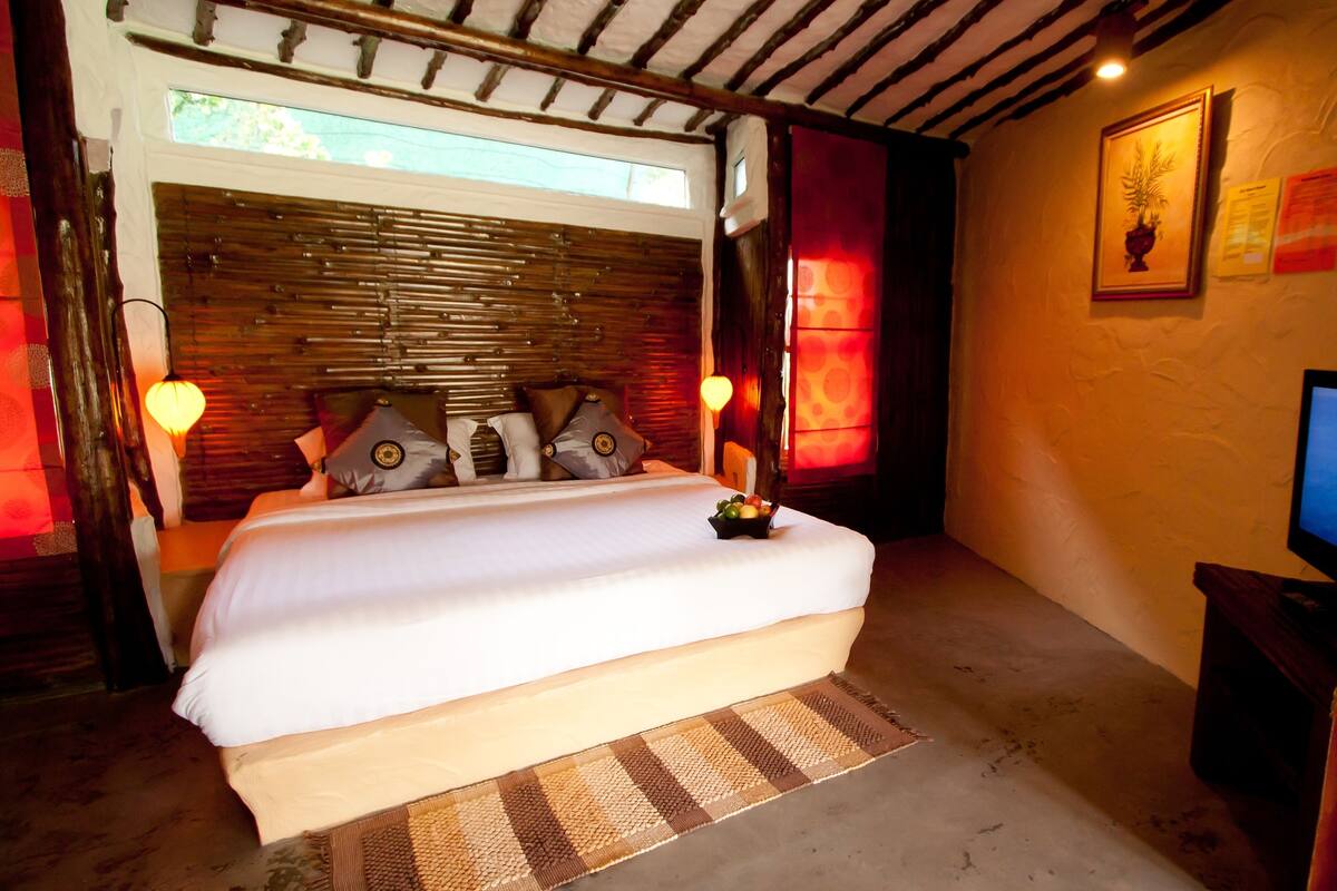 A bedroom with a bed, a television, and a window.