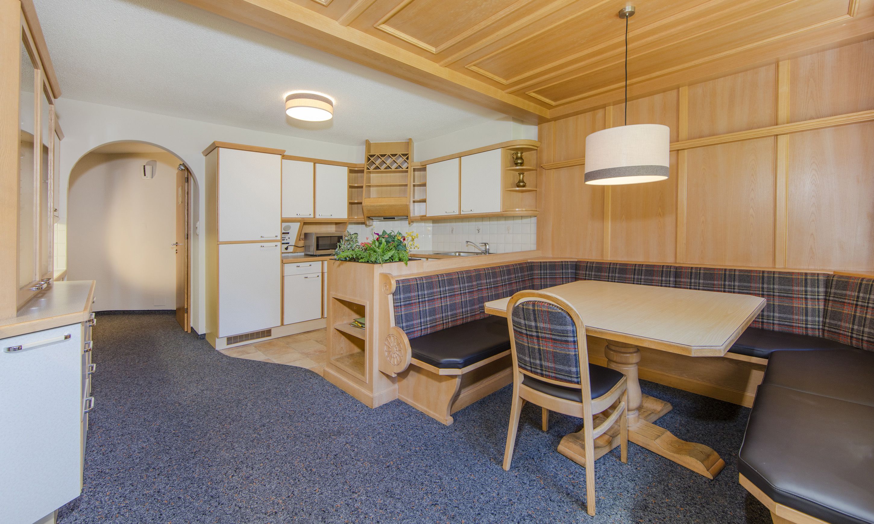 A compact kitchen with a dining area, including a bench and a table.