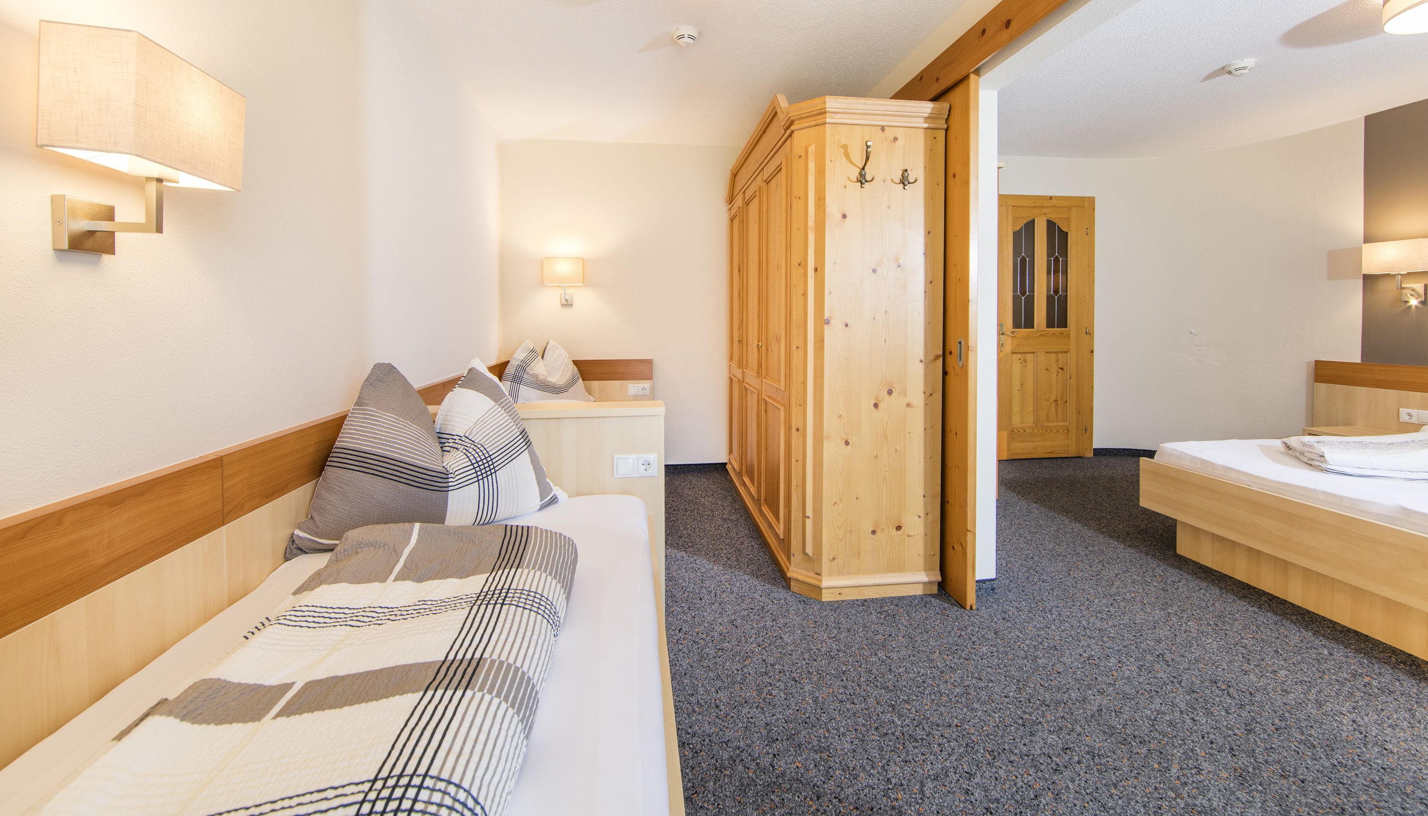 A hotel room with a bed, a wardrobe, and a mirror.