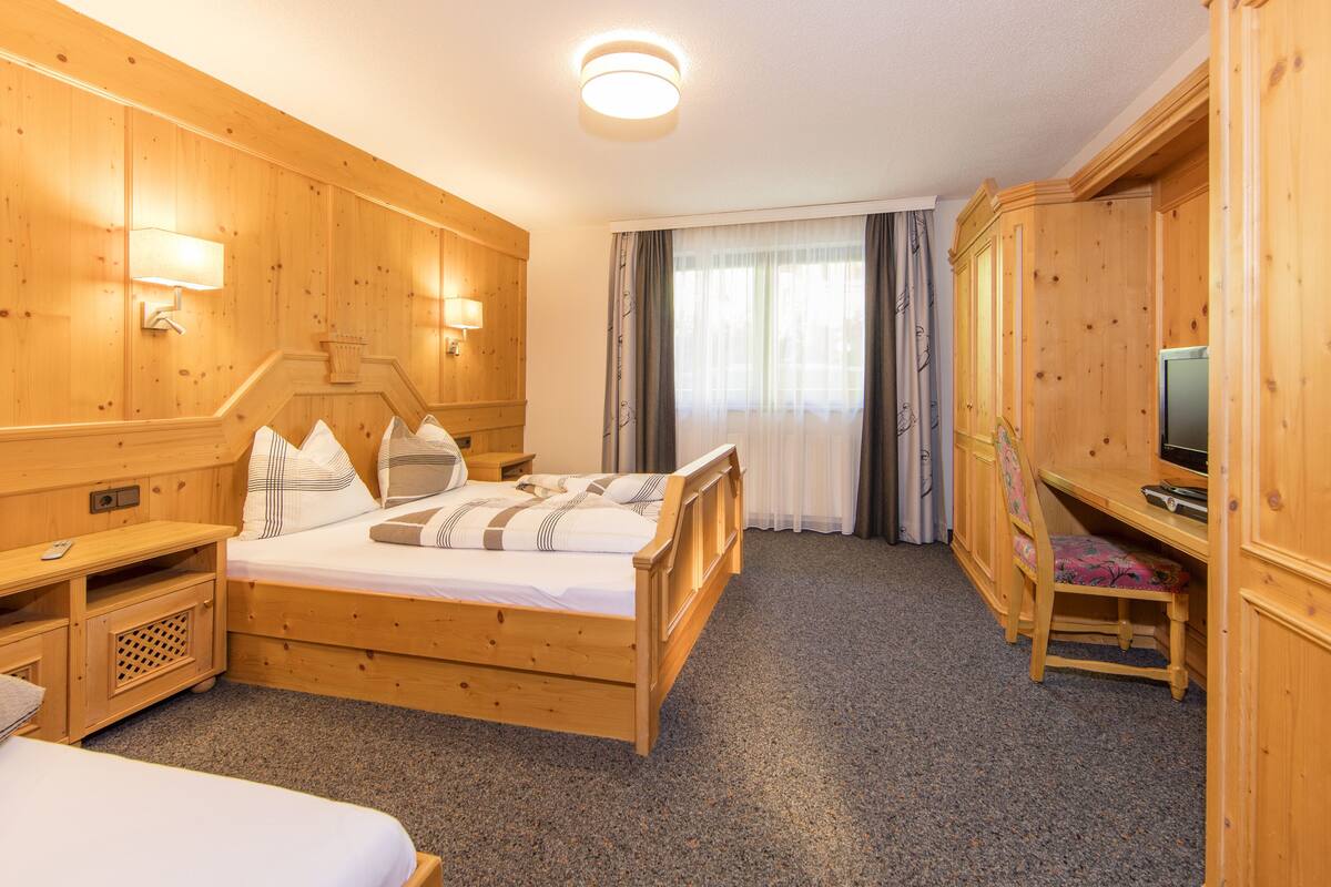 A wooden room with a bed, a TV, and a desk.