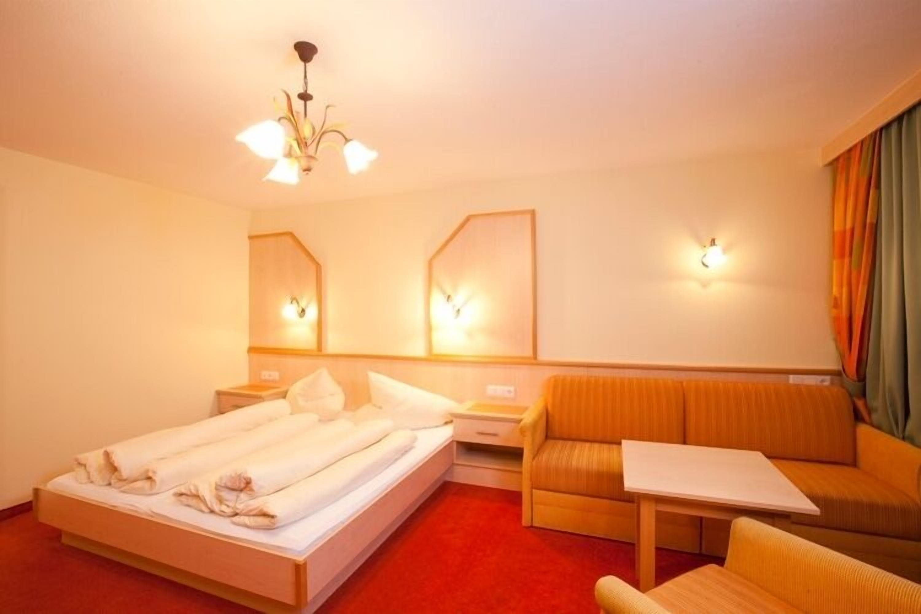 Ein Hotelzimmer mit einem Bett, einer Schlafcouch, einem kleinen Tisch und zwei Wandleuchten.