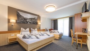 Una camera d'albergo con un grande letto, una scrivania, una sedia, un televisore e un quadro appeso al muro.