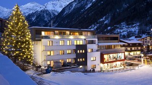 Un hotel moderno con diversi piani, un abete di Natale ben visibile e uno sfondo montuoso.