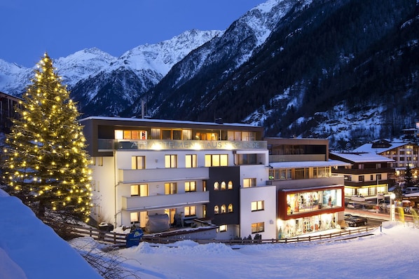 A modern hotel with multiple floors, a prominent Christmas tree, and a mountain backdrop.