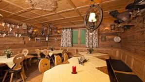 Un interno rustico in legno con tavoli e panche di legno, un lampadario e teste di animali appese alle pareti.