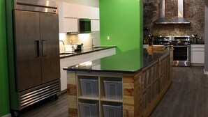 Een moderne keuken met een groot eiland, roestvrijstalen apparatuur en een groene accentmuur.