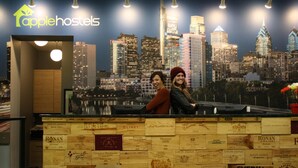 Een receptiebalie met een stadsgezicht op de achtergrond, met het logo van 'applehostels'.