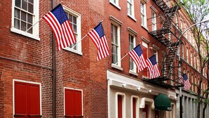 Een gebouw van rode baksteen met meerdere ramen, een vluchttrap en verschillende Amerikaanse vlaggen.