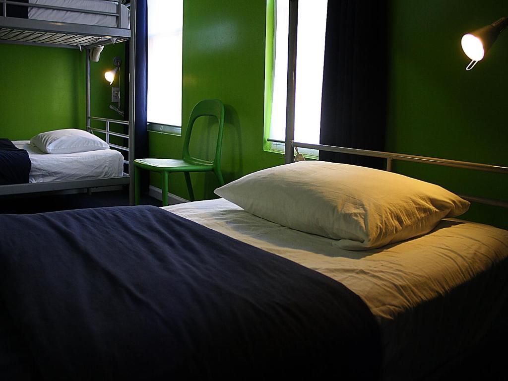 A bunk bed with a pillow, a chair, and a window with curtains.