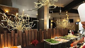 A buffet setup with various dishes and a modern interior design including wooden accents and unique lighting fixtures.