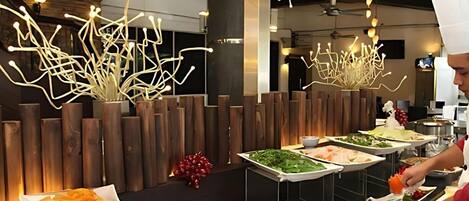 A buffet setup with various dishes and a modern interior design including wooden accents and unique lighting fixtures.