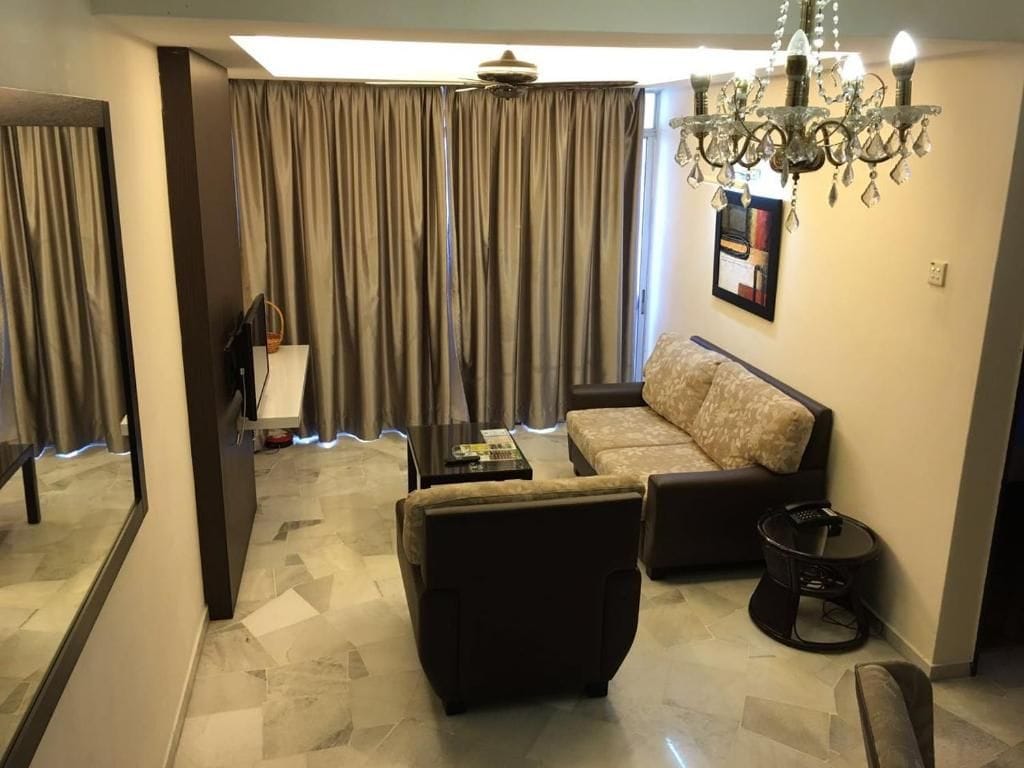 A living room with a sofa, armchair, coffee table, and a chandelier.