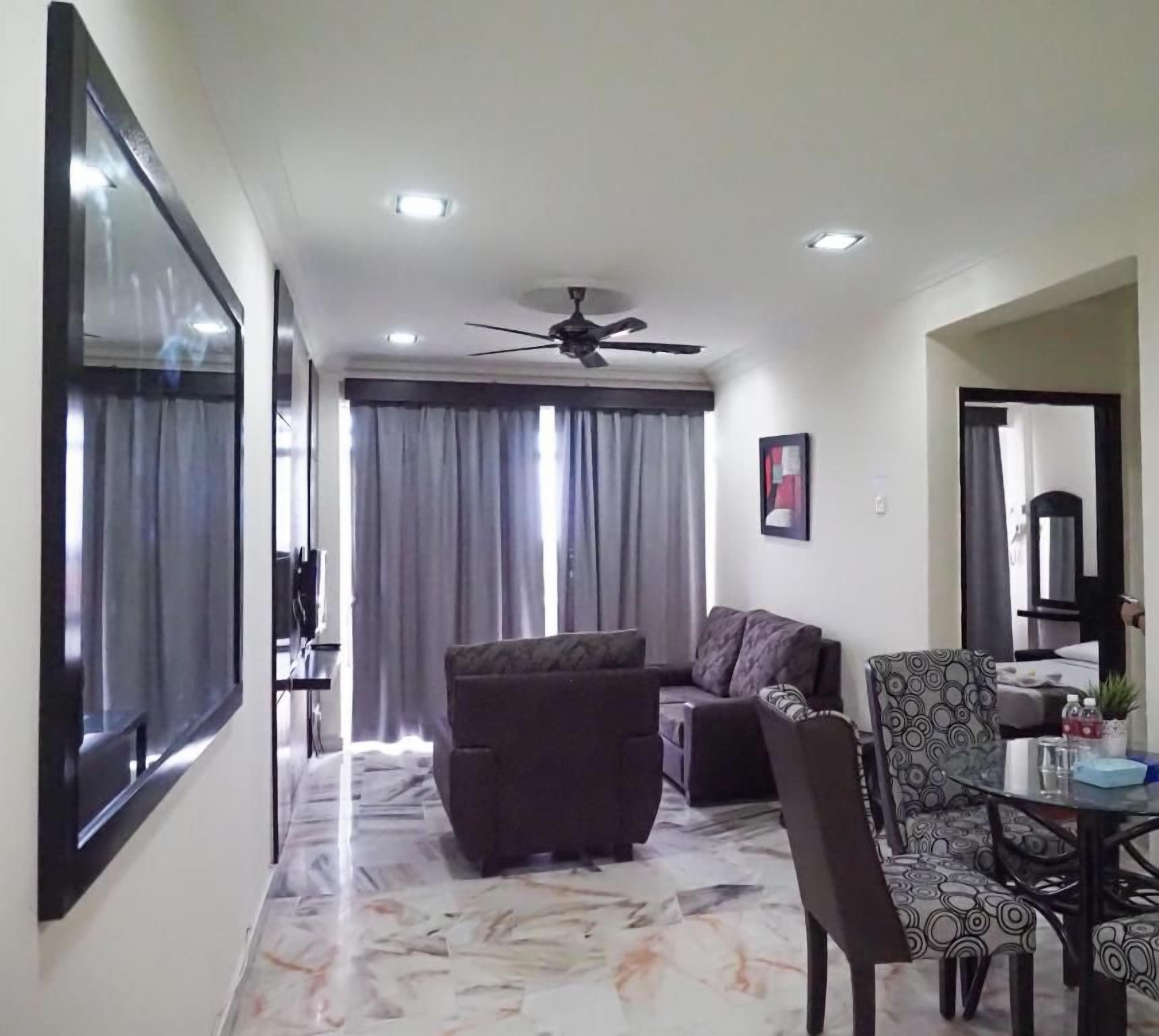 A living room with a sofa, armchair, and a dining table with chairs.