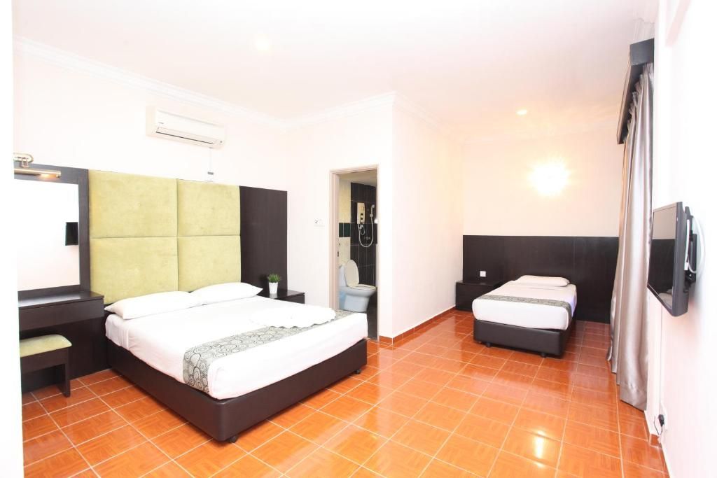 A hotel room with a large bed, a smaller bed, a desk, a chair, and a bathroom visible through an open door.