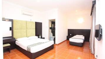 A hotel room with a large bed, a smaller bed, a desk, a chair, and a bathroom visible through an open door.