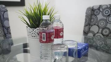 Una mesa de vidrio con una planta en maceta, dos botellas de agua y un caja azul.
