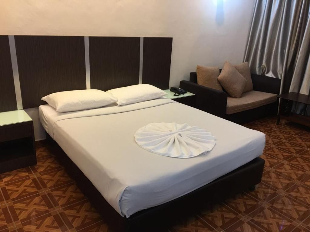 Ein Hotelzimmer mit Bett, Nachttisch, Sofa und einem gemusterten Boden.