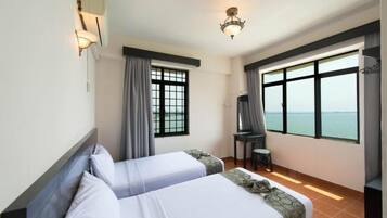 Habitación de hotel con dos camas, un escritorio, una silla, una ventana con vistas y una lámpara en el techo.