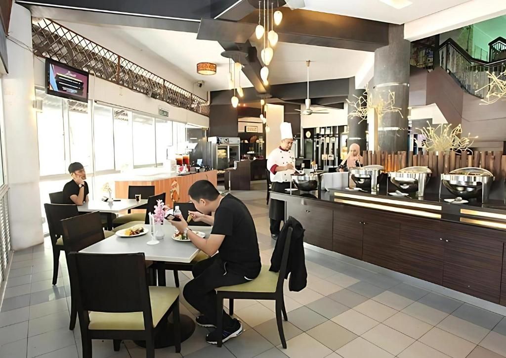 Interior de un restaurante moderno con comedor, cocina y una escalera que sube a un nivel superior.