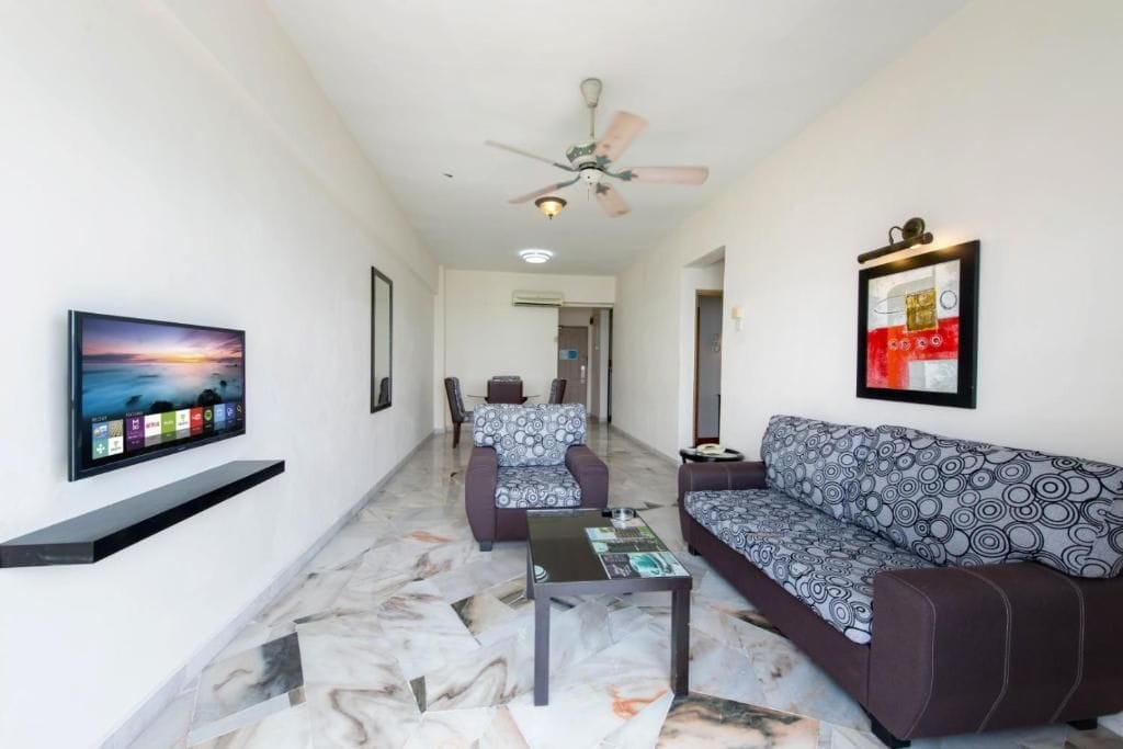 A modern living room with a sofa, a coffee table, and a television mounted on the wall.