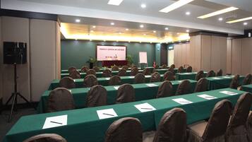 A conference room with rows of tables and chairs, a podium, and a presentation screen.